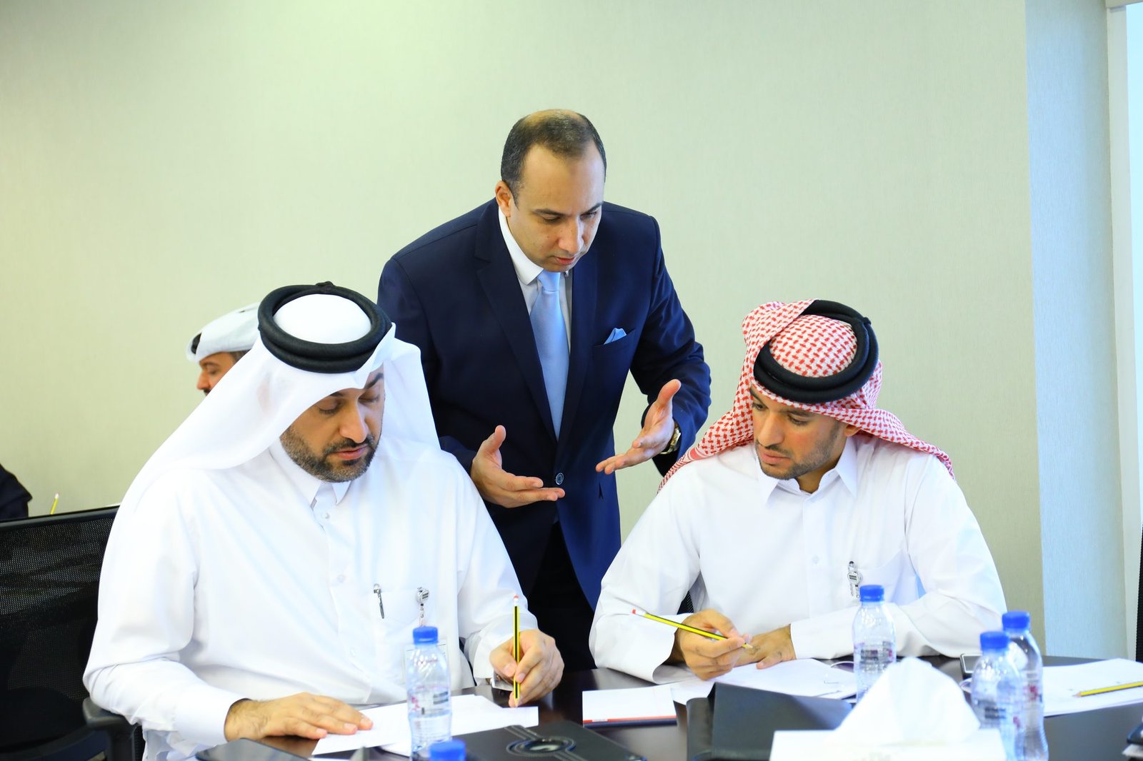 Mostafa Azzam leaning in to guide two delegates through an exercise at their table